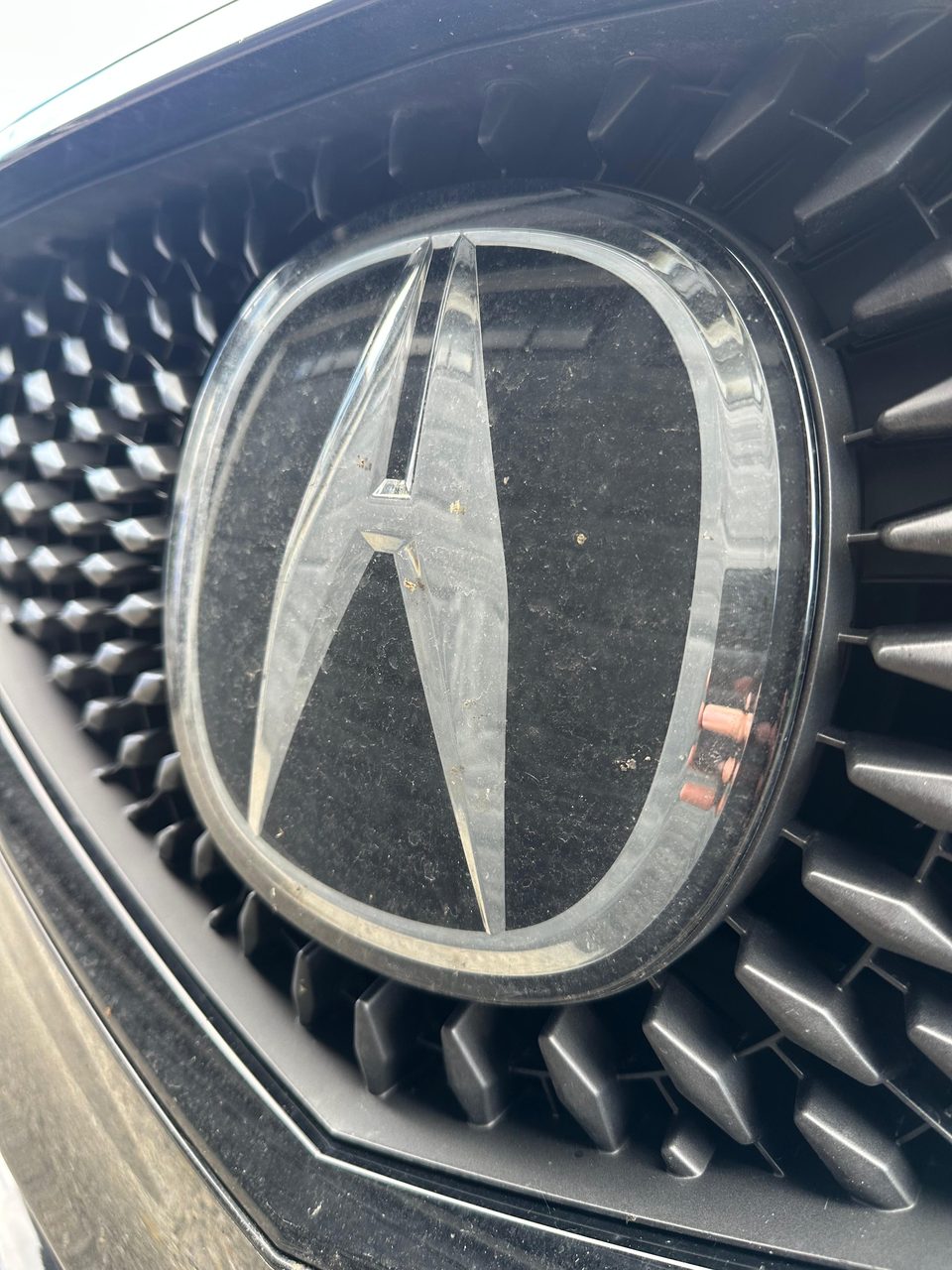 Dirty car grille emblem before detailing — Arc Detailing Calgary